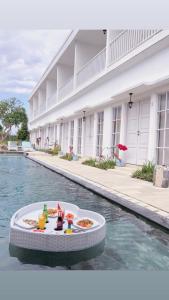 a table with food and drinks on a float in the water at Hikari Guesthouse in Seminyak