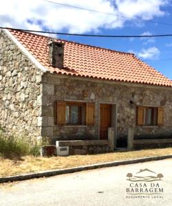 una pequeña casa de piedra con techo rojo en Casa da Barragem en Montalegre