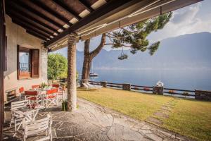 a patio with a table and chairs and a view of the water at OSSUCCIO PRIVATE POOL VILLA ON THE LAKE-by Italian Apartments in Como
