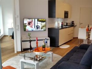 uma sala de estar com um sofá e uma televisão na parede em Ferienwohnung Koralle - Am Wasser em Bremerhaven