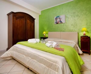 zieloną sypialnię z łóżkiem i ręcznikami w obiekcie Sosta dei Garibaldini w mieście Campofelice di Roccella
