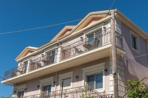an apartment building with balconies on a blue sky at Pansion Ermioni in Skala