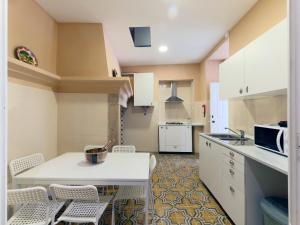 a kitchen with white cabinets and a table and chairs at Casa do Doutor in Portalegre