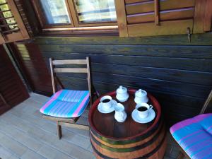 a wooden table with cups and plates and a chair at VILLA KORANA in Barilović
