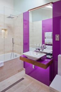 un bagno viola con lavandino e vasca di City Suites a Londra