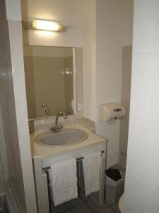 a bathroom with a sink and a mirror at HOTEL De La Tour Saint Etienne SUD in Saint Etienne
