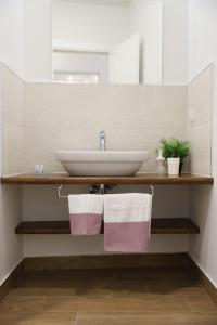 a bathroom with a sink and two towels on a shelf at TalialETNA Apartments in Nicolosi