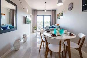 a dining room and living room with a table and chairs at Apartament BLUE Gardenia Dziwnów in Dziwnów