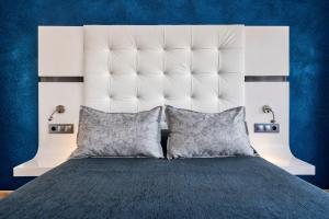 a bed with a large white headboard and two pillows at Salles Hotels Marina Portals in Portals Nous