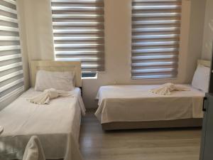 2 camas en una habitación con sábanas blancas y ventanas en Taksim Square Apart Hotel, en Estambul