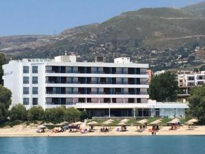 Apollon Suites في كاريستوس: فندق على الشاطئ وبه كراسي ومظلات