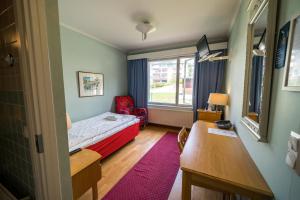 um pequeno quarto com uma cama, uma secretária e uma janela em Karolineburg Manor House Hotel em Kajaani
