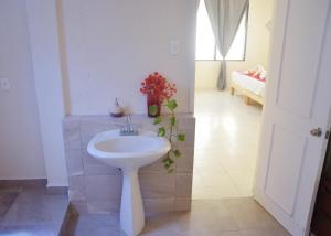 a bathroom with a white sink and a bedroom at CASA BUGAMBILIAS in Cancún