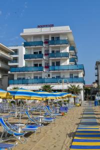 una spiaggia con sedie e ombrelloni e un hotel di Hotel Souvenir a Lido di Jesolo