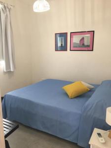 a blue bed in a bedroom with two pictures on the wall at Casa Vigna da Michela in Favignana