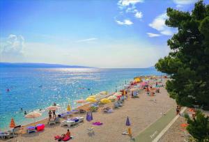 a beach with a bunch of people and umbrellas at Vintage House for rent 60m from Sea in Baška Voda
