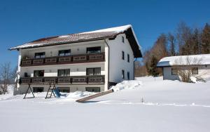 ein weißes Gebäude mit Schnee davor in der Unterkunft Ferienwohnung Haus Franziska in Neuschönau