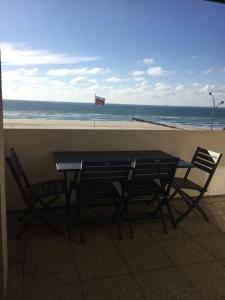 a table and chairs next to a beach with a flag at Studio pleine vue sur l'océan - Soulac sur Mer in Soulac-sur-Mer