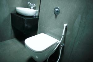 a bathroom with a white toilet and a sink at Hotel Highnest in Singapperumālkovil