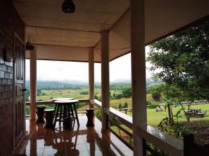 a porch with a table and a view of a field at มนต์เมืองแจ่ม in Mae Chaem