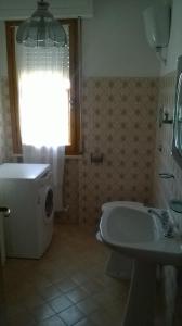 a bathroom with a toilet and a sink and a window at Appartamento grazioso e confortevole a Orbetello (GR) in Orbetello