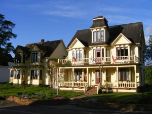 uma grande casa amarela com um grande alpendre em The Maple Inn em Parrsboro