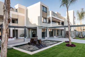 a large white building with palm trees in front of it at Porto Platanias Beach Luxury Selection - Adults Only in Plataniás