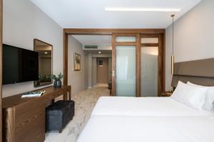 a hotel room with a bed and a television at Porto Platanias Beach Luxury Selection - Adults Only in Plataniás