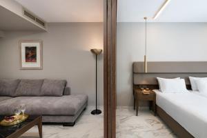 a hotel room with a bed and a couch at Porto Platanias Beach Luxury Selection - Adults Only in Plataniás