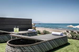 a patio with a table and chairs and the beach at Porto Platanias Beach Luxury Selection - Adults Only in Plataniás