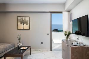 a living room with a couch and a tv at Porto Platanias Beach Luxury Selection - Adults Only in Plataniás