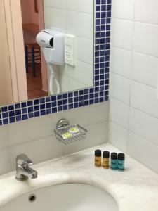 a bathroom sink with three different colored jars on it at Apollon Suites in Karistos