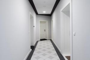 einen Flur mit weißen Wänden und einem schwarz-weißen Fliesenboden in der Unterkunft Loft Apartments Poznań in Posen