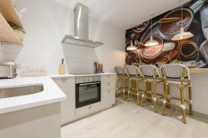 a kitchen with white cabinets and gold chairs at Minty Stay - Malasaña in Madrid
