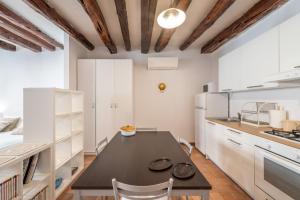 una cucina con tavolo nero e armadietti bianchi di Remy apartment a Cagliari
