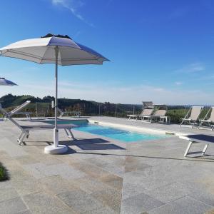 a pool with a table and an umbrella and chairs at Villa Vecchio in Castagnito