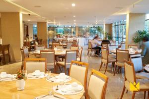restauracja ze stołami i krzesłami oraz osobami w tle w obiekcie Brasília Imperial Hotel e Eventos w mieście Brasília
