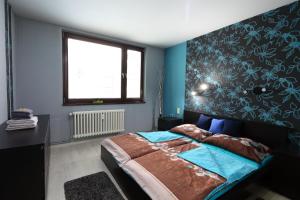 Schlafzimmer mit einem Bett mit blauen Wänden und einem Fenster in der Unterkunft Apartmán 77 in Loučná nad Desnou