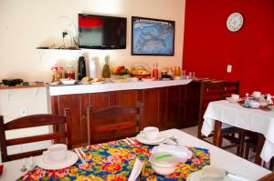 una cocina con 2 mesas y una pared roja en Pousada Luzes de Geribá, en Búzios