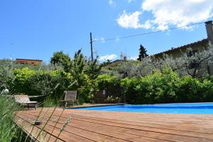 um jardim com um deque de madeira e uma piscina em Casale Asciolo em Bagno a Ripoli