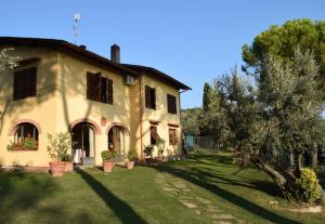 a large yellow house with a tree in the yard at Casale Asciolo in Bagno a Ripoli