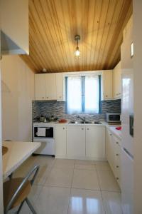 a kitchen with white cabinets and a wooden ceiling at Under the Windmills in Kondiás