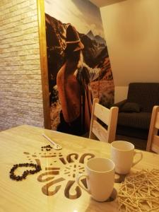 une table avec deux tasses et une pancarte sur celle-ci dans l'établissement Apartament Folk&Dream Harenda Zakopane, à Zakopane