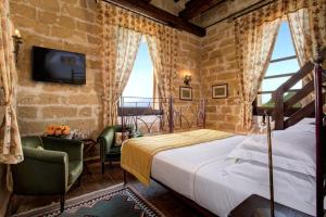 马尔萨拉Hotel Baglio Oneto dei Principi di San Lorenzo - Luxury Wine Resort的一间带床、电视和窗户的卧室
