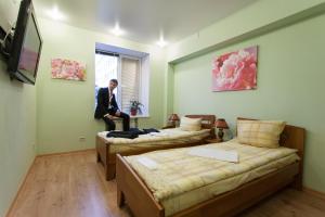 un hombre está de pie en una habitación con dos camas en Вятские улочки центр, en Kirov