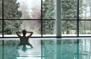 a woman sitting in a swimming pool in front of a window at Kurhaus Marienkron in Mönchhof