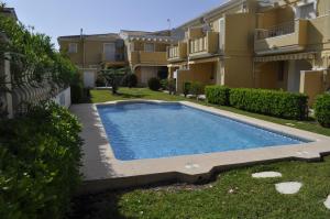 a swimming pool in a yard next to a building at Acogedor adosado duplex in Els Poblets