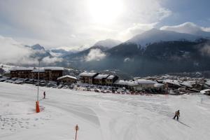 two people skiing down a snow covered slope in front of a resort at Le Duplex d'Aussois in Aussois