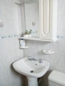 a white bathroom with a sink and a toilet at DEPARTAMENTOS Las Araucarias- 2 a 5 personas con estacionamiento in Neuquén