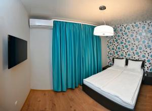 1 dormitorio con cama y cortina azul en Varchev 1, en Varna